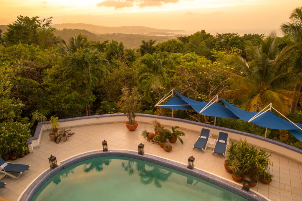 View of Hotel Mocking Bird in Port Antonio, surrounded by lush green hills and the beach.